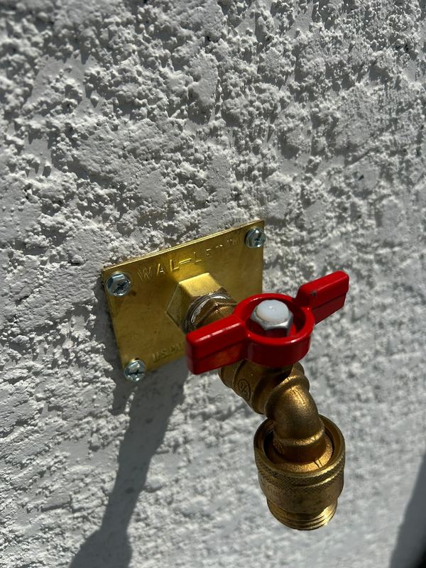 New brass hose bibb set on a stucco exterior